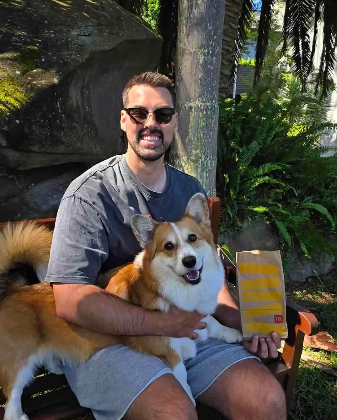 AussieAntics holding his dog and a McDonald's bag.