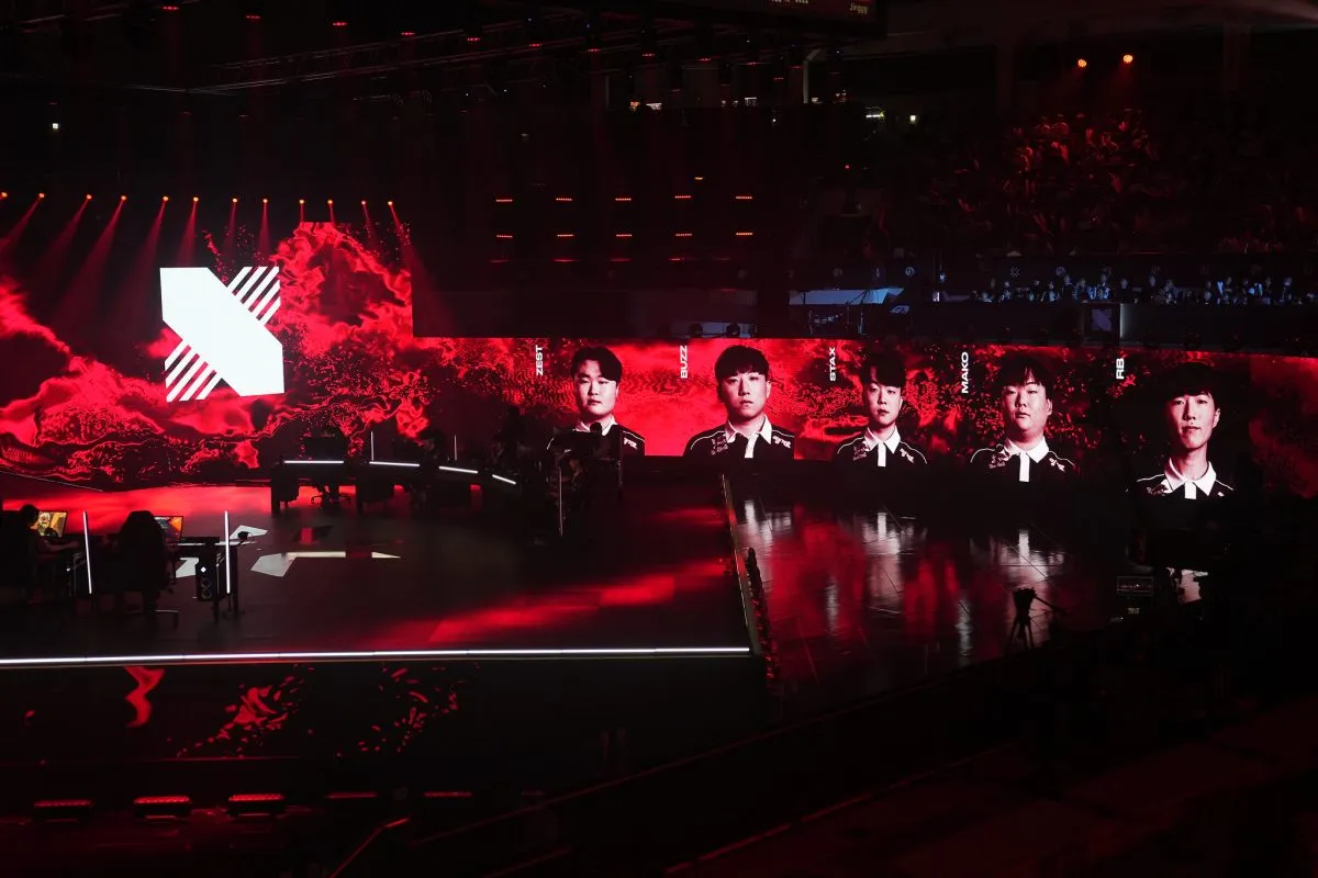 DRX and PRX sit on the VCT Pacific grand finals stage. Behind the DRX players' desks is a screen showing each players gamer tag and portrait.