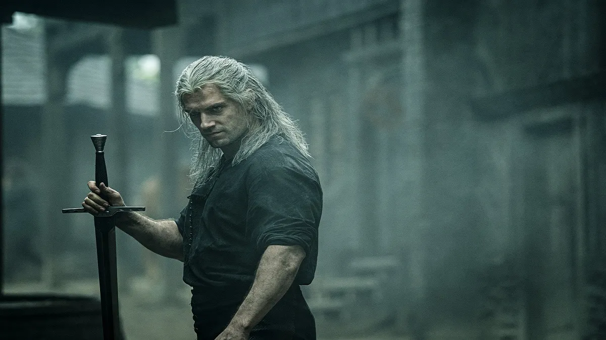 An image of Henry Cavill as Geralt of Rivia brandishing a sword in The Witcher Netflix show.