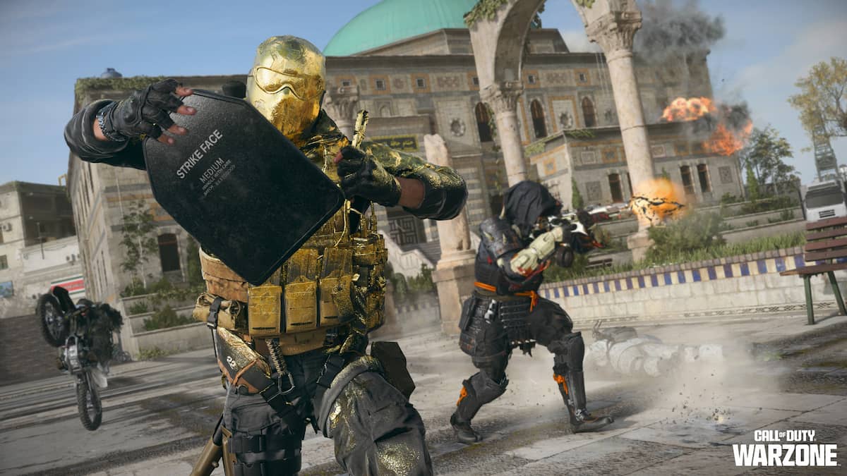 An operator covered in a shiny gold operator skin equips a shield pack while others fire weapons around them.